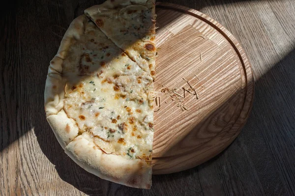 Meia Pizza Uma Bandeja Madeira Está Uma Mesa Iluminada Pelo — Fotografia de Stock