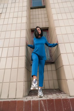 Koyu renk saçlı kız şehirde mavi bir takım elbiseyle dolaşıyor.