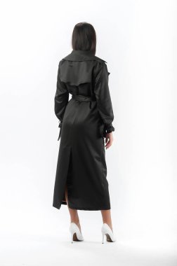 Esmer, beyaz arka planda bir katalog için kıyafetlerle poz veriyor.