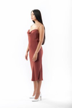 Esmer, beyaz arka planda bir katalog için kıyafetlerle poz veriyor.