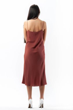 Esmer, beyaz arka planda bir katalog için kıyafetlerle poz veriyor.