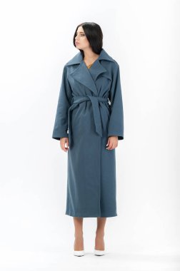 Esmer, beyaz arka planda bir katalog için kıyafetlerle poz veriyor.