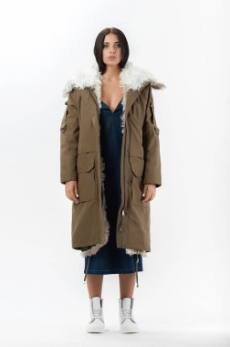 Esmer, beyaz arka planda bir katalog için kıyafetlerle poz veriyor.