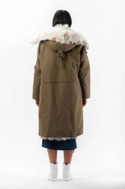 Esmer, beyaz arka planda bir katalog için kıyafetlerle poz veriyor.