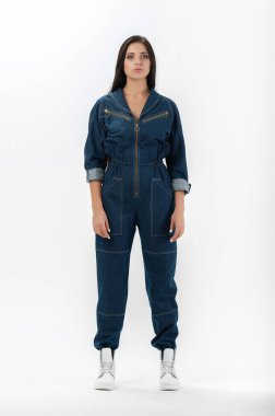 Esmer, beyaz arka planda bir katalog için kıyafetlerle poz veriyor.