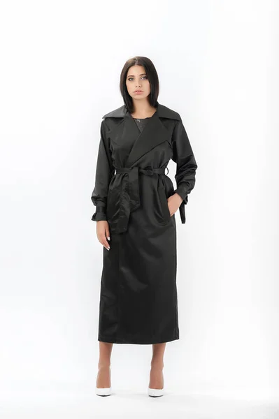 Esmer, beyaz arka planda bir katalog için kıyafetlerle poz veriyor.