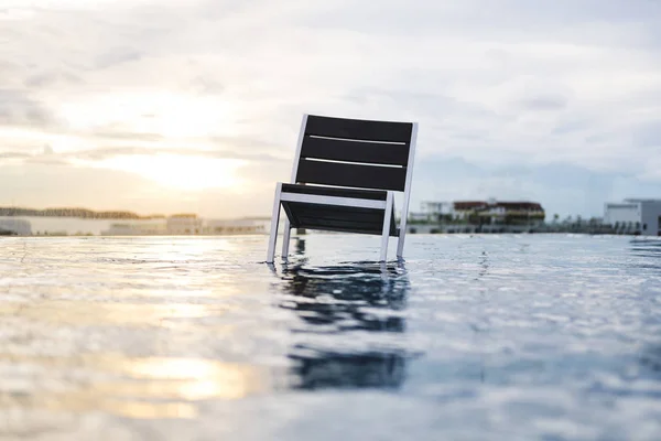 Una silla de pie sobre el agua al atardecer — Foto de Stock