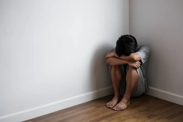 Jeune homme déprimé assis seul dans le coin de la pièce, la tristesse, la dépression et les problèmes de la vie concept — Photo