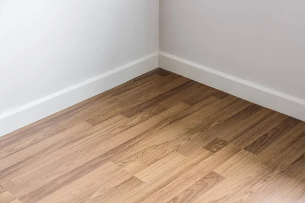 Laminowane podłogi z drewna z biała ściana, rogu pokoju — Zdjęcie stockowe