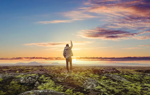 男と日の出の美しいコケに覆われた溶岩が空まで腕を上げる — ストック写真