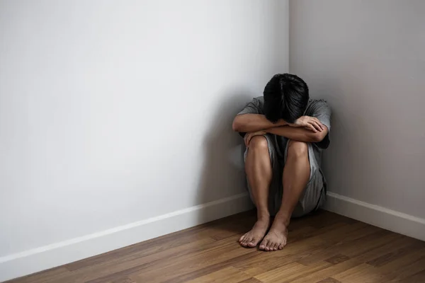 Депрессивный молодой человек сидит в одиночестве в углу комнаты, грусть, депрессия, и жизнь проблемы концепции — стоковое фото