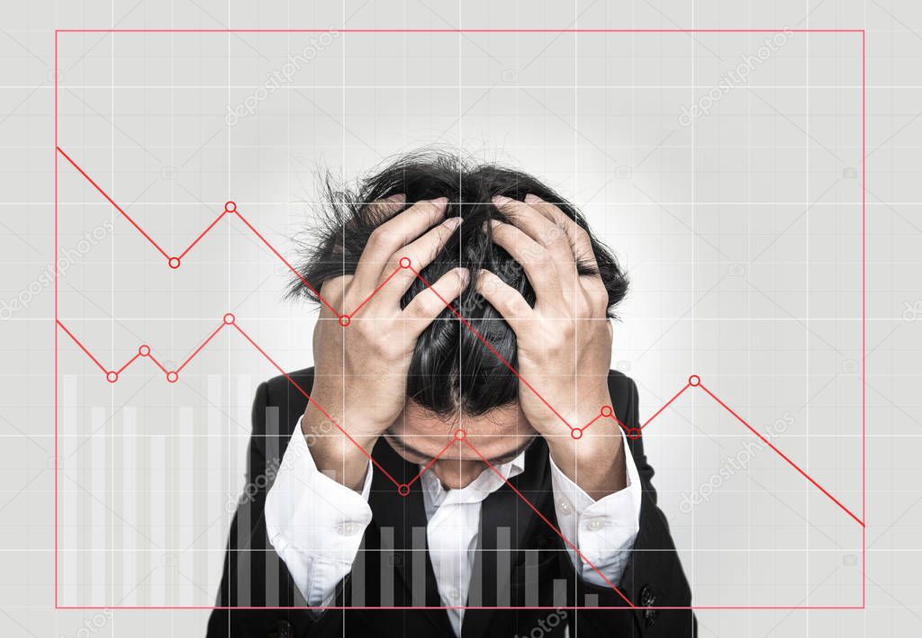 Stressed out businessman, with downward business graphs. Failure stock market and loss business investment profit concepts