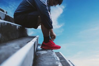 Asya adam ipe koşu için çalışan, mavi gökyüzü arka plan ile hazırlama ayakkabı,