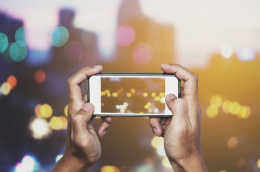 Fotoğrafta akıllı telefon tarafından Bokeh ışıklar parti alarak smartphone holding eller