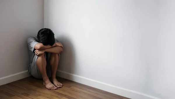 Un ragazzo seduto da solo in un angolo di stanza, tristezza, depressione e problemi di vita concetto — Foto Stock