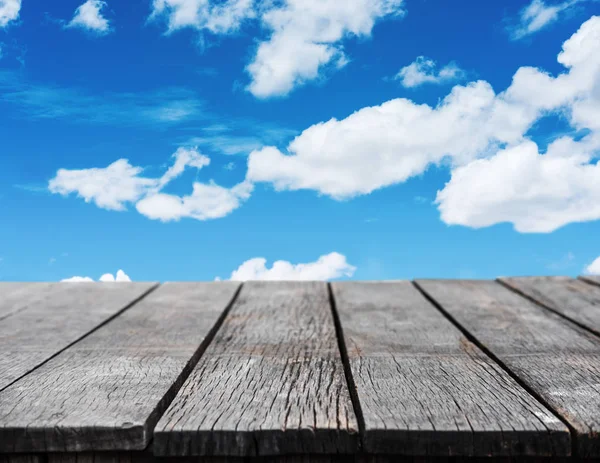 Wooden table with blue sky and white cloud background