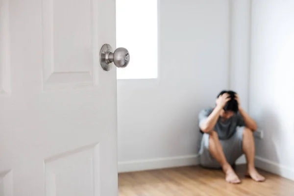 Door opened with depressed guy sitting in corner of empty room