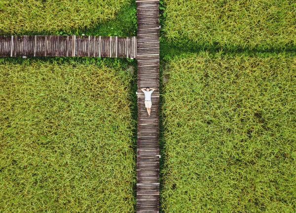 Vista superior, un tipo relajándose en camino de madera en el campo de arroz verde, feliz fin de semana en el campo —  Fotos de Stock
