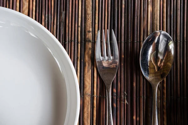 Yakın çekim çatal kaşık ve beyaz tabak ahşap masa mat ile