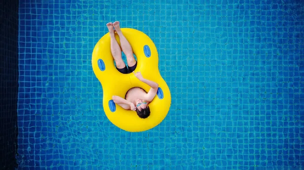 Vista superior, um homem relaxando no flutuador amarelo da piscina, na piscina no verão — Fotografia de Stock