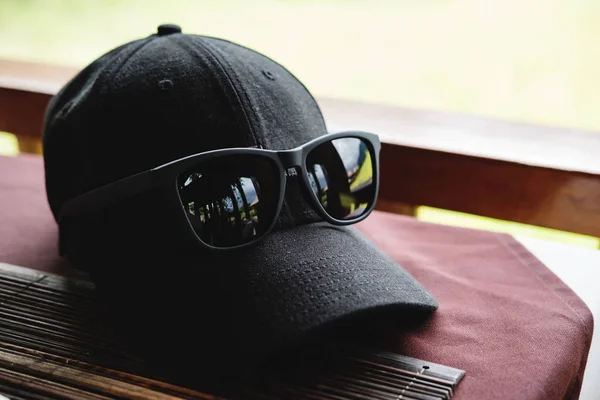 Schwarze Mütze und schwarze Sonnenbrille auf dem Tisch — Stockfoto