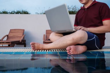 havuz kenarında, seçici odak oturan dizüstü bilgisayarda çalışan bir adam