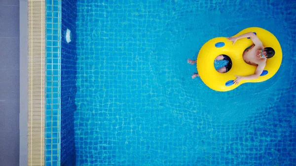 Vista aérea, um homem relaxa no flutuador amarelo da piscina, na piscina no verão — Fotografia de Stock