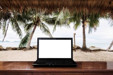Yaz aylarında sahilde ahşap masa üstünde bilgisayar laptop. Kırpma yolu bilgisayar ekran
