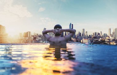 bir adam sabah şehir manzarayı sunrise, yüzme havuzunda rahatlayın