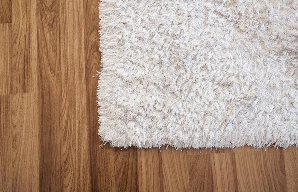 Alfombra blanca de primer plano sobre piso de madera laminada en sala de estar, decoración interior —  Fotos de Stock