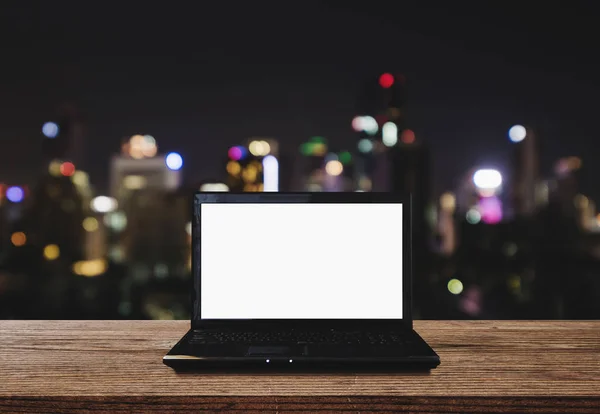 Dator bärbar dator på trä skrivbord med Bokeh ljus av staden på natten bakgrund. Klippning sökvägen datorskärm — Stockfoto