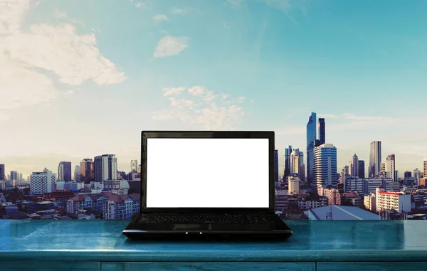 Přenosný počítač prázdná bílá obrazovka na dřevo stůl s pozadím panoráma města Bangkok — Stock fotografie