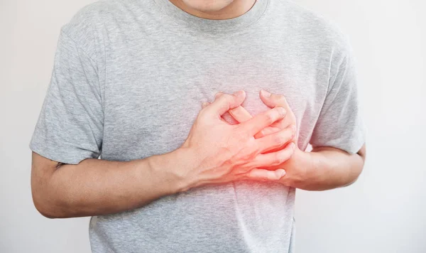 Человек, трогающий свое сердце, с красной изюминкой сердечного приступа, и другие концепции болезни сердца, на белом фоне — стоковое фото