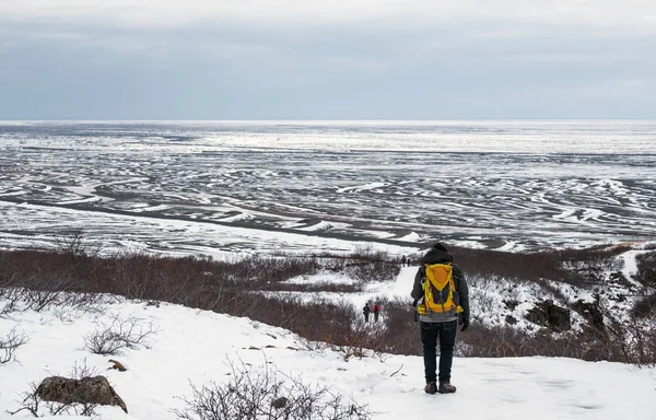 Um homem com mochila amarela andando na montanha de neve no inverno, na Islândia — Fotografia de Stock