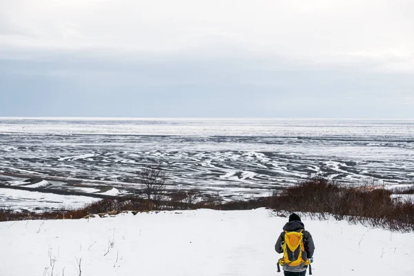 Um homem com mochila amarela andando na montanha de neve no inverno, na Islândia — Fotografia de Stock