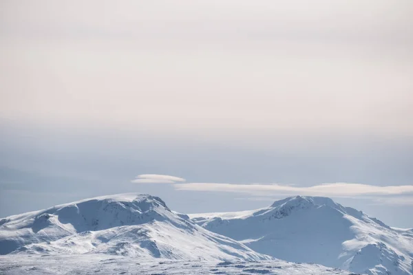 雪は、アイスランドの冬の風景、冬に山のピークおよび白い雲と青い空を頂いた — ストック写真