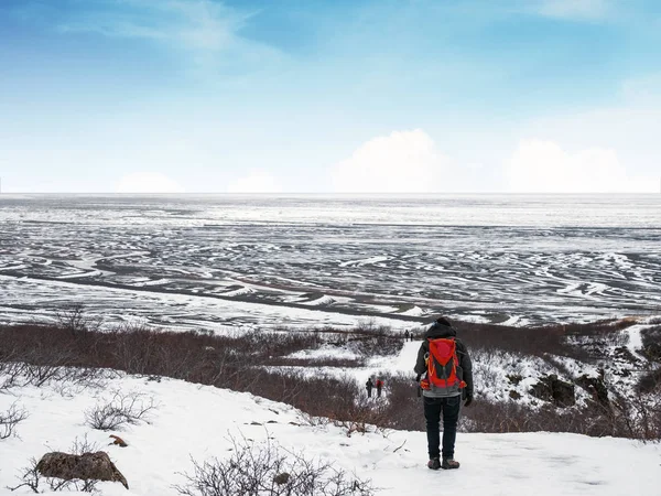 빨간 배낭에 아이슬란드에서 겨울에 눈이 산에 걷는 남자 — 스톡 사진