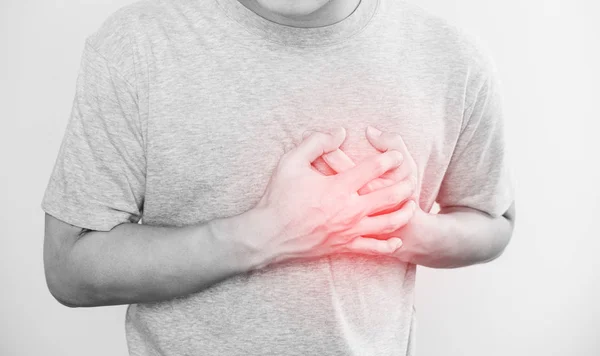 Человек, трогающий свое сердце, с красной изюминкой сердечного приступа, и другие концепции болезни сердца, на белом фоне — стоковое фото