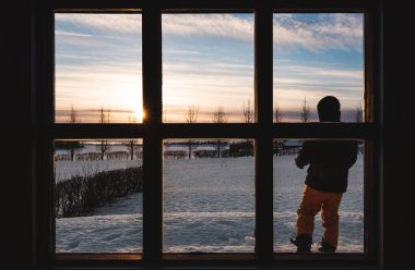 Sabahları tek başına duran bir adam ile kış gündoğumu pencereden bakıyor