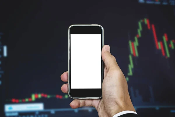 Main tenant téléphone intelligent mobile, écran vertical blanc vierge, fond graphique du marché boursier — Photo