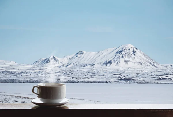 Чашка гарячого напою з парою на дерев'яному столі і красивий зимовий краєвид вранці — стокове фото