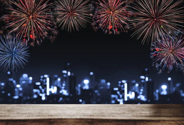 Festival fireworks at night in the city, wooden desk with Bokeh lights of building at night. For Holiday festival, New years and celebration background