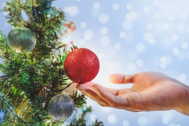 Arka plan bulanıklık Bokeh ile tatil dekorasyon için Noel ağacı üzerinde kırmızı Noel topları tutan el ışıklar