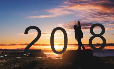 Kayanın üzerinde ayakta, el altında günbatımı kadar yükselterek man özgürlük siluet. 2018 yeni yıl kutlama