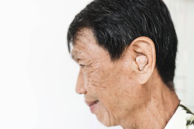 Yakın çekim kıdemli Asya adam kulak giyen işitme cihazı, gülen yüz, kulak, beyaz arka plan üzerinde tarih seçici odak ile Audiphone,