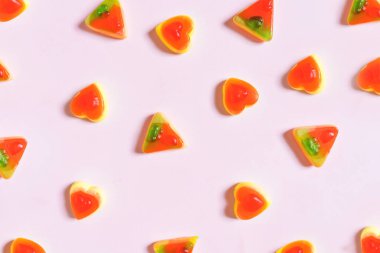 Pastel pembe bir arka plan üzerinde renkli jöle, pizza ve kalp şekli