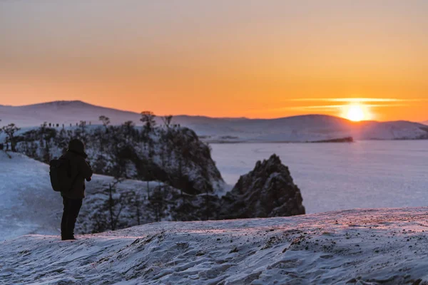 イルクーツク ロシアのバイカル湖で冬のご旅行 夕暮れの美しい夕焼けを楽しむ若いカメラマンと日没の冬の風景 — ストック写真