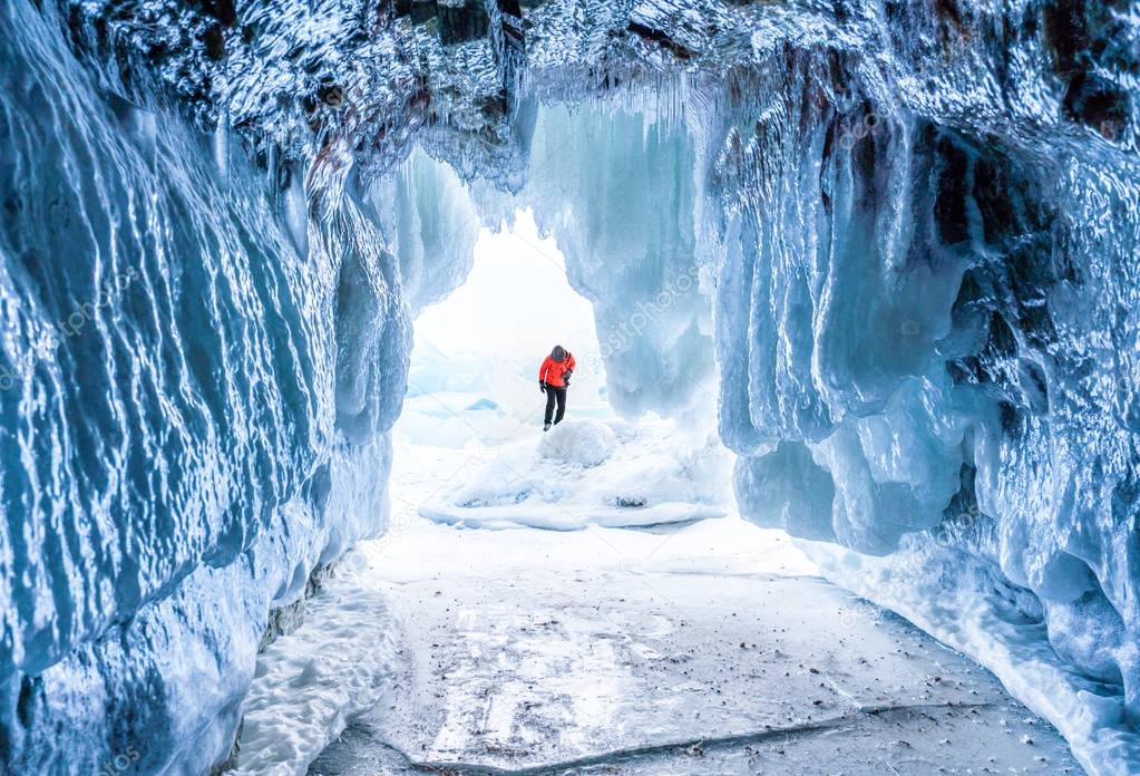 Winter Landscape, Frozen ice cave with young photographer standing alone. Traveling in winter