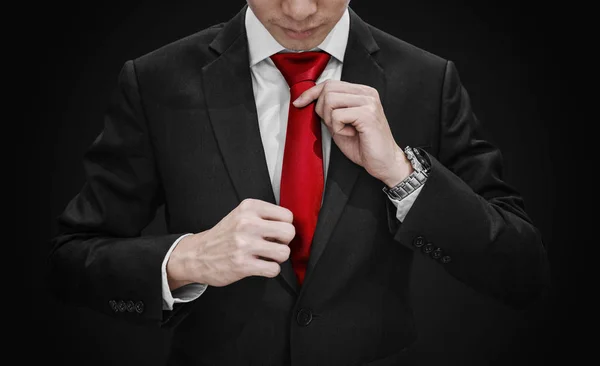 Geschäftsmann Schwarzen Anzug Bindet Rote Krawatte Auf Schwarzem Hintergrund — Stockfoto
