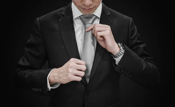 Hombre Traje Negro Atando Corbata Gris Sobre Fondo Negro — Foto de Stock